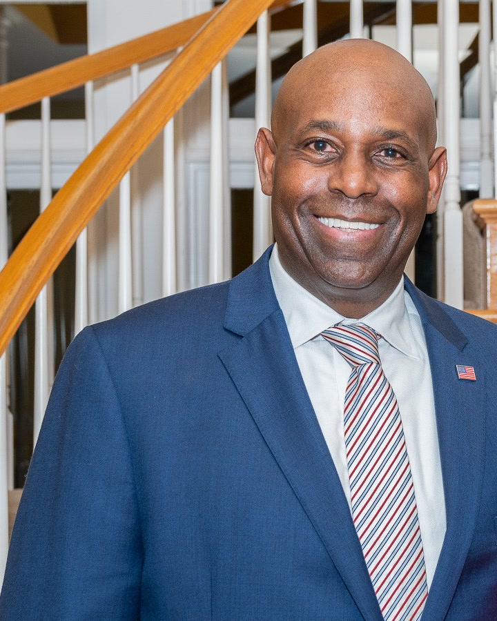 Forest Hayes smiling in a navy suit with an American flag lapel pin